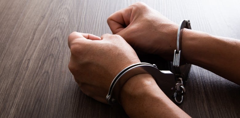 person in handcuffs at table