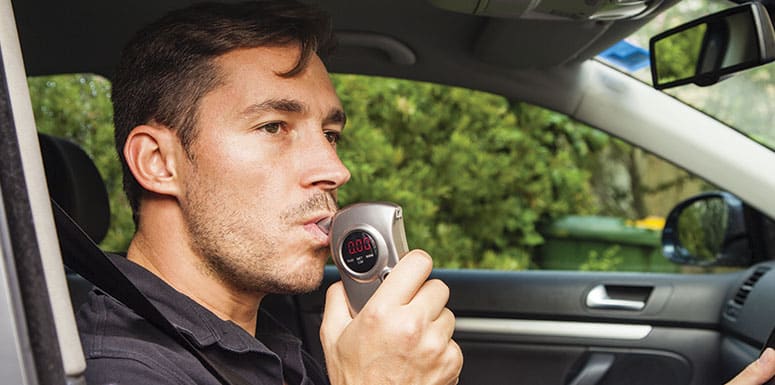 drunk driver blowing on breathalyzer