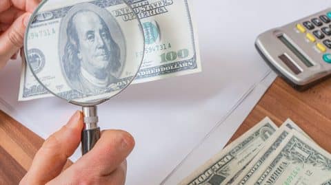 Magnifying Glass Being Used by a Sex Crimes Attorney to Determine the Effects of a Conviction on a Client's Finances