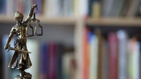 Justice statue with gavel in front of books