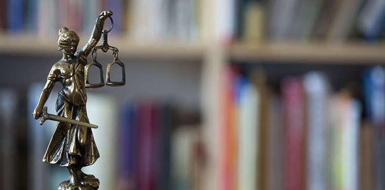 Justice statue with gavel in front of books