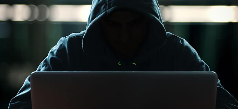 hooded figure using laptop