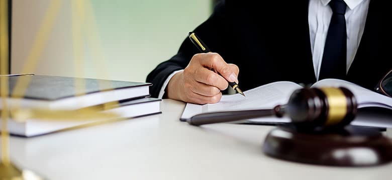 man signing document in front of gavel