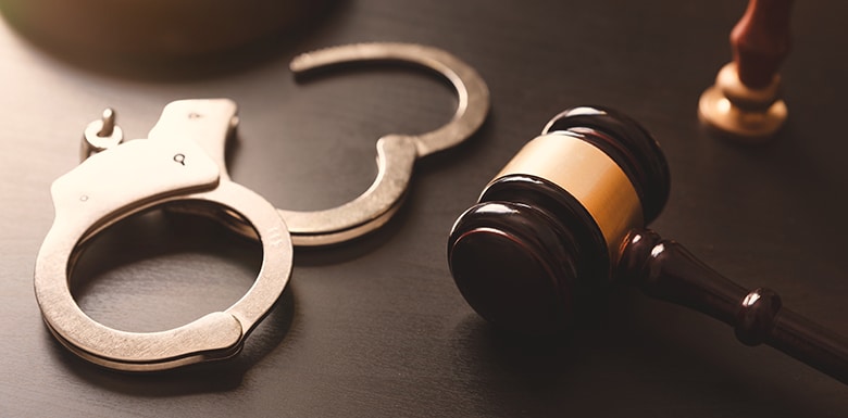 Gavel and handcuffs on table in dark lighting