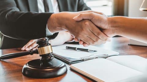 Attorney shaking hands over desk with client