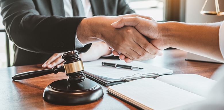 Attorney shaking hands over desk with client