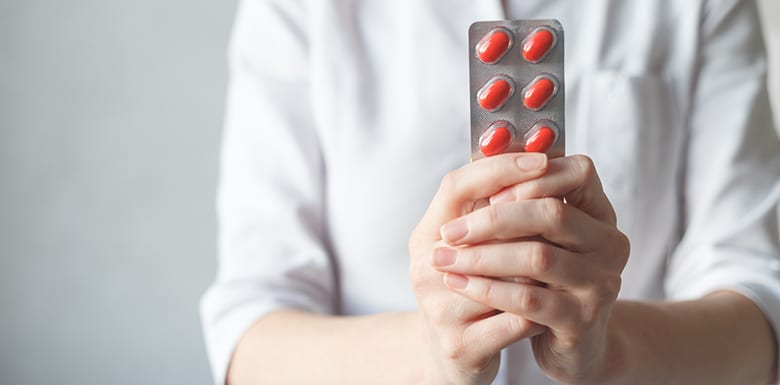 Woman in white shirt offering orange pills