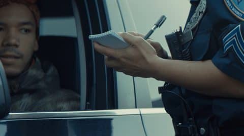 Police officer writing ticket at window of pulled over car