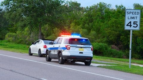 Police car with lights on pulled over a white car