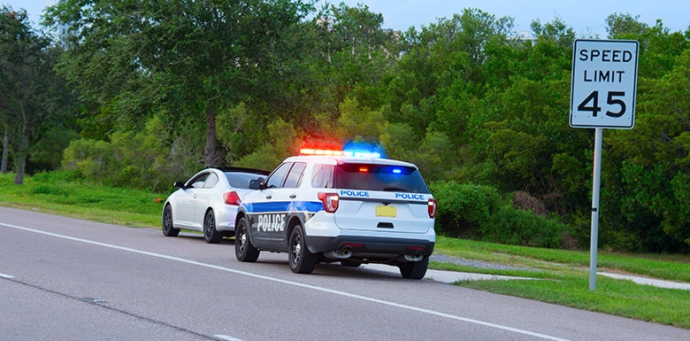 Police car with lights on pulled over a white car