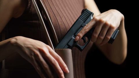 Woman putting handgun in purse