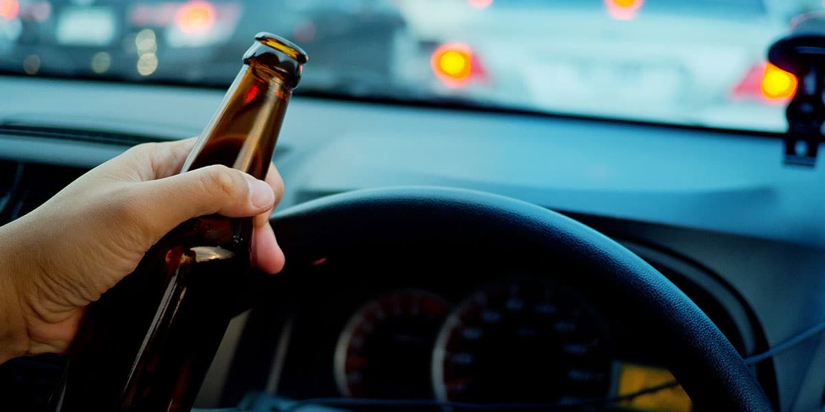 Man holding a beer while driving while intoxicated