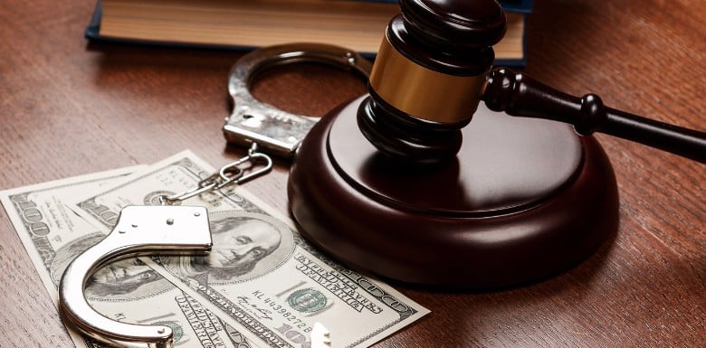 A gavel with money and handcuffs on a table to represent bail