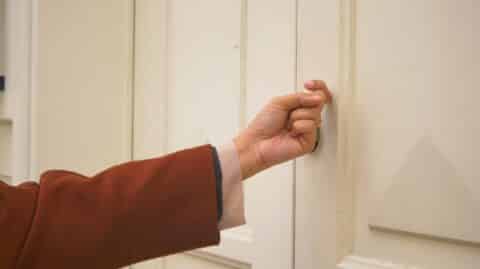 Hand knocking on door to do a search