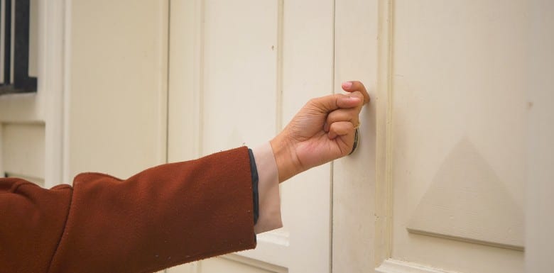 Hand knocking on door to do a search