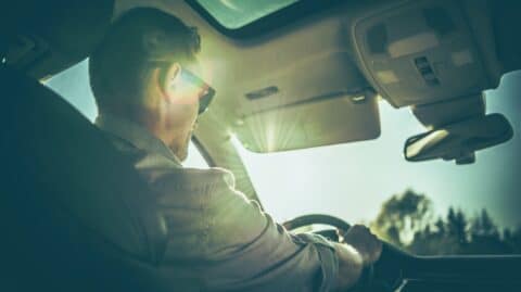 Man driving a car with sunlight through the windshield, symbolizing regained DUI driving privileges in Columbus, Ohio.