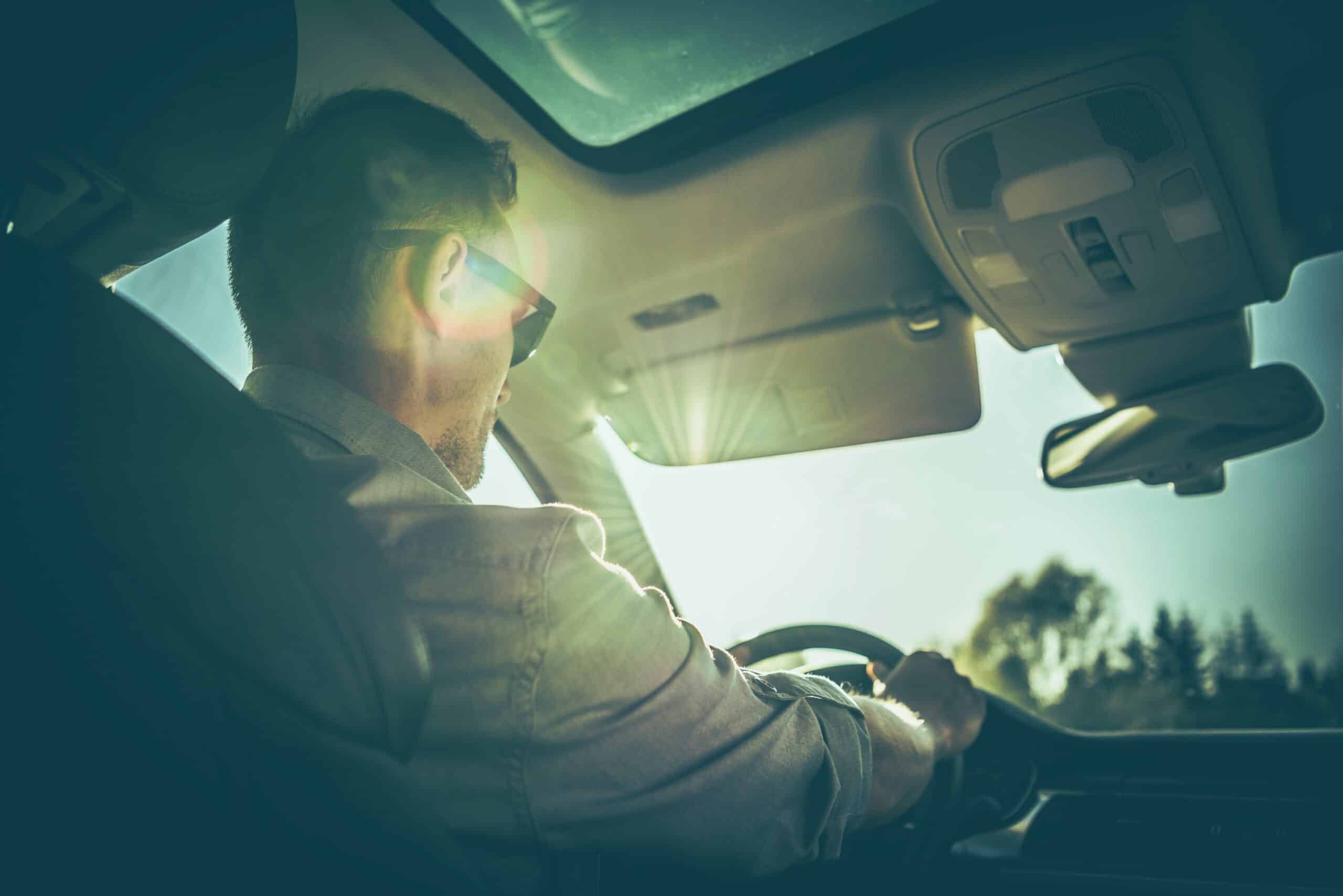 Man driving a car with sunlight through the windshield, symbolizing regained DUI driving privileges in Columbus, Ohio.